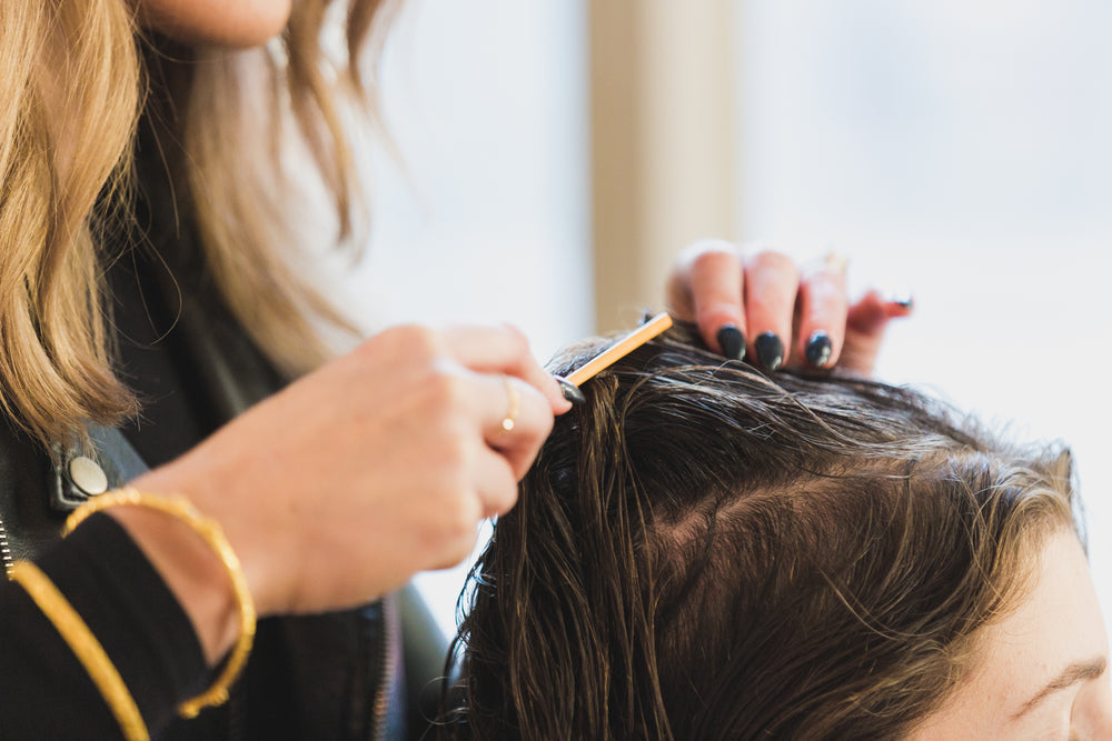 A stylist parting hair with a tail comb.