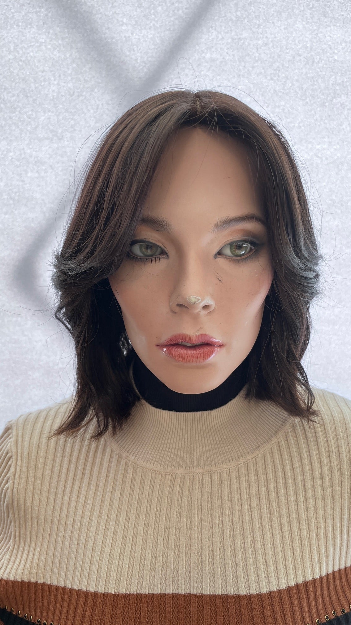 Front view of the dark brown Fortune wig with bangs and soft waves on a mannequin