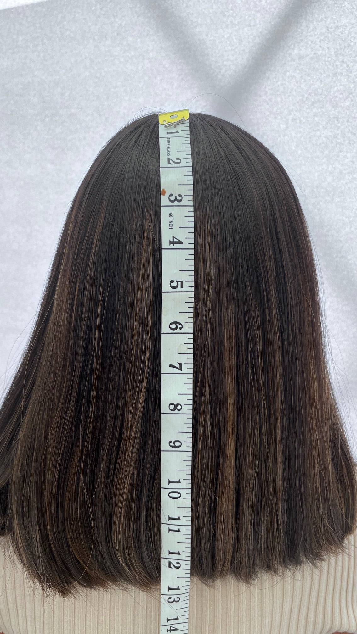 Back view of the Gali wig beside a measuring tape
