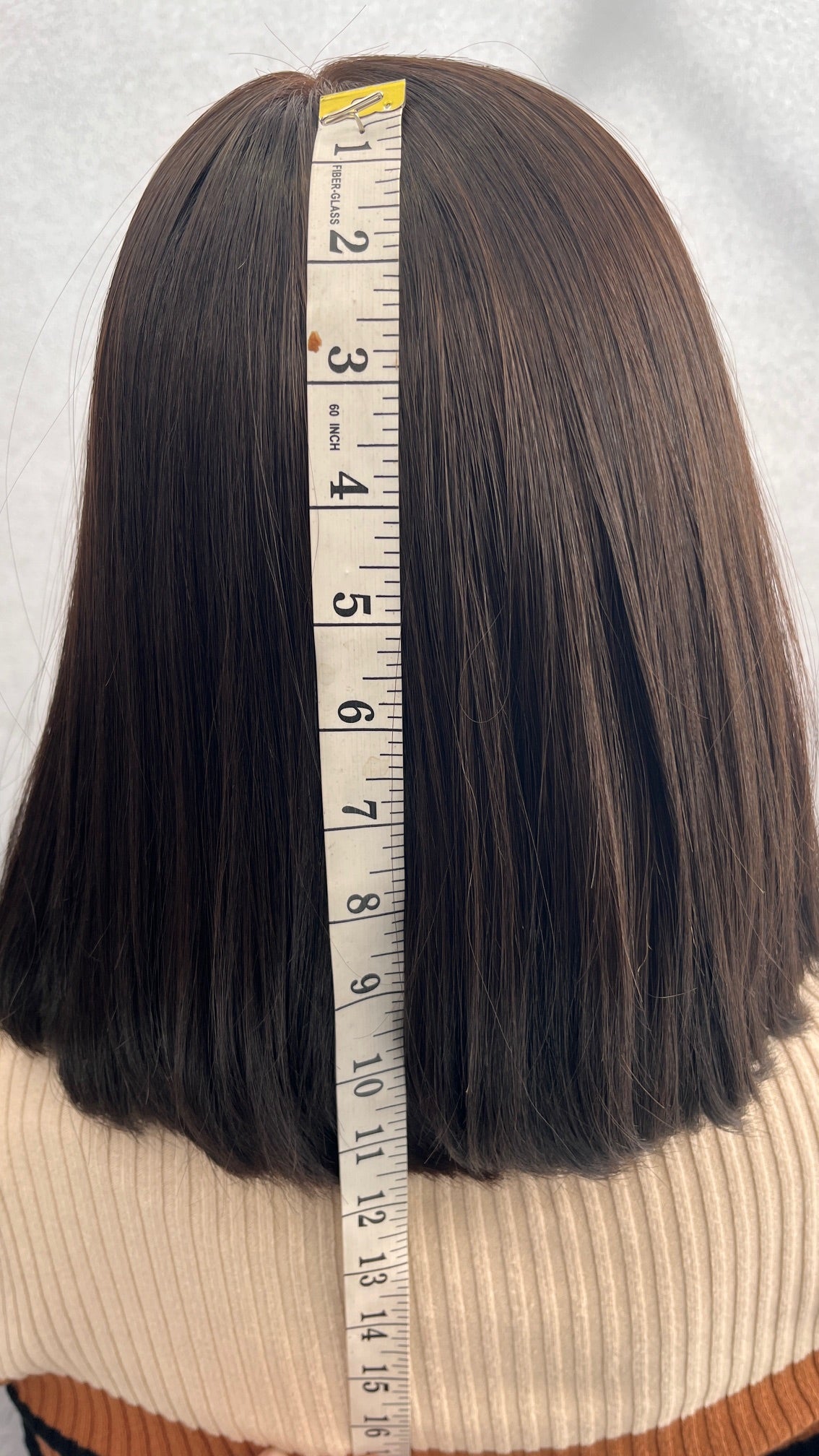 Back view of the Fortune wig beside a measuring tape