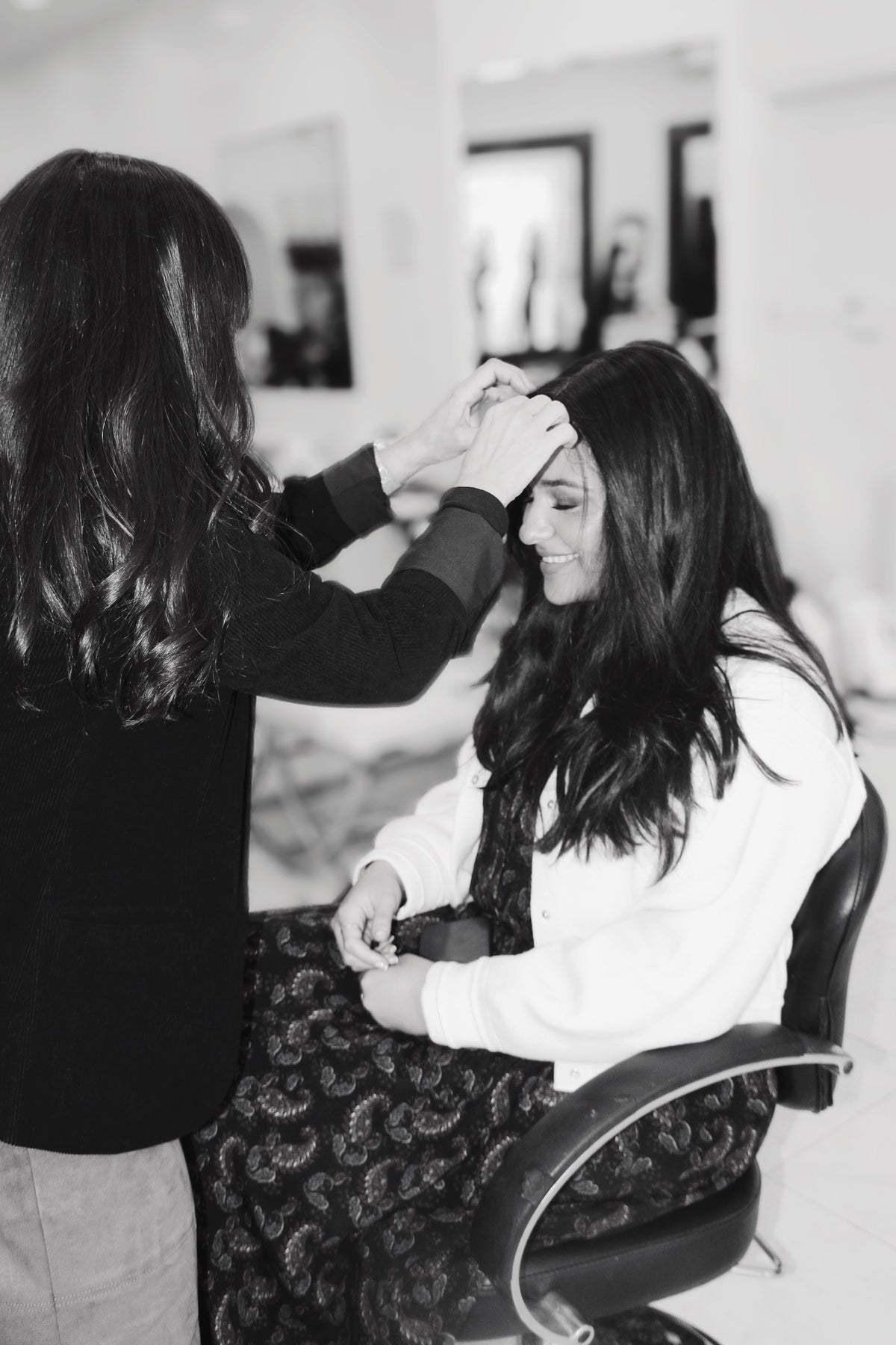 A stylist working with a seated client in the salon, shown on the wig-repair shipping page.