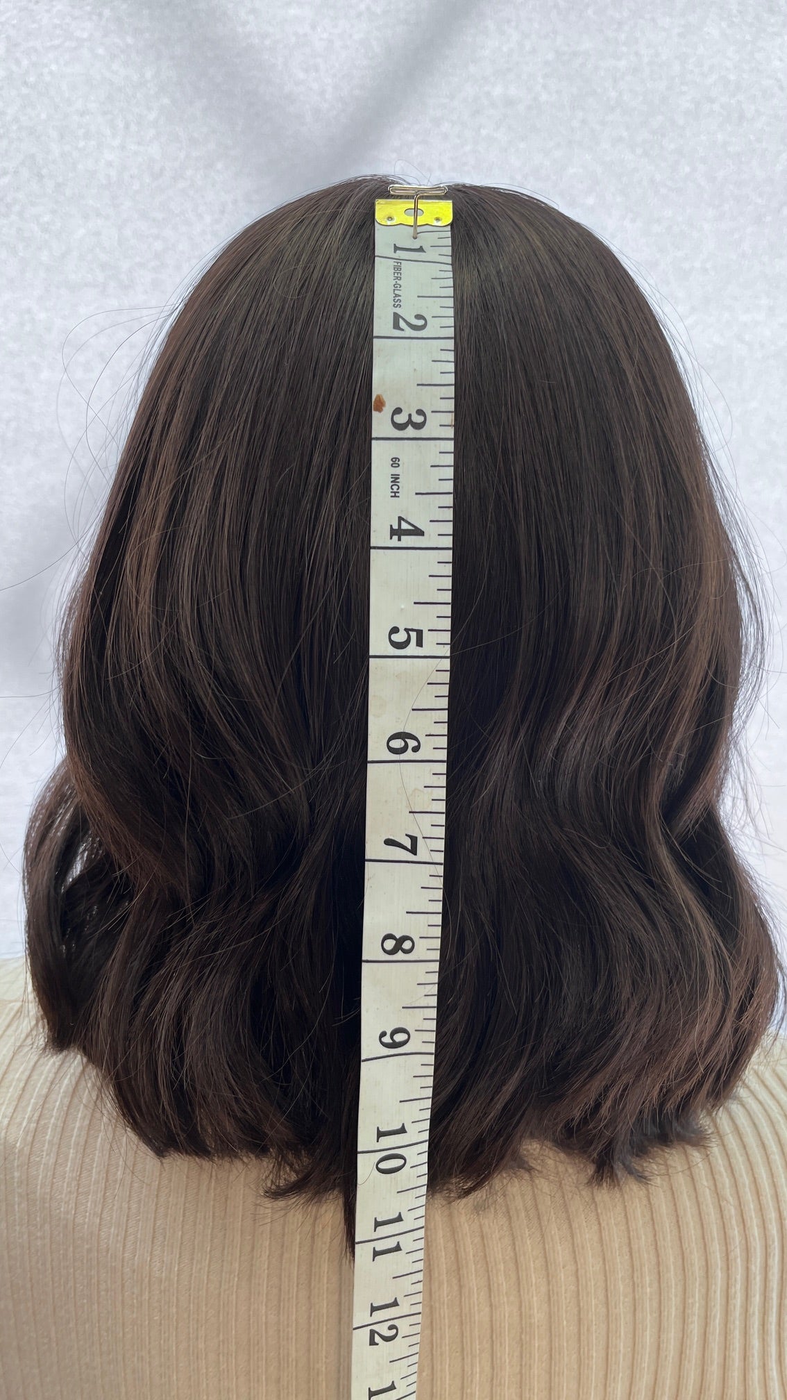 Back view of the Fortune wig beside a measuring tape